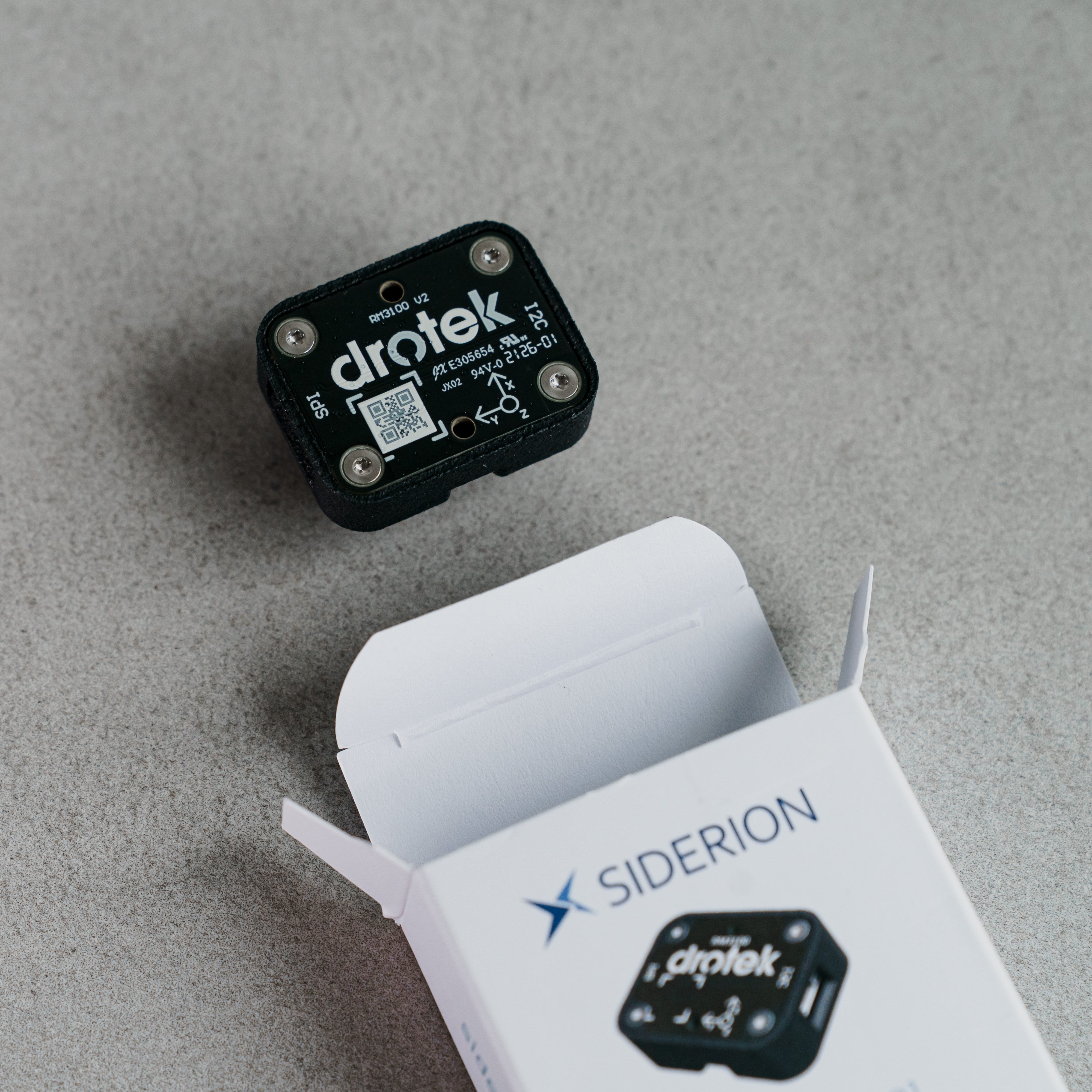 Siderion RM3100 professional magnetometer sensor on a gray background with its packaging box open.
