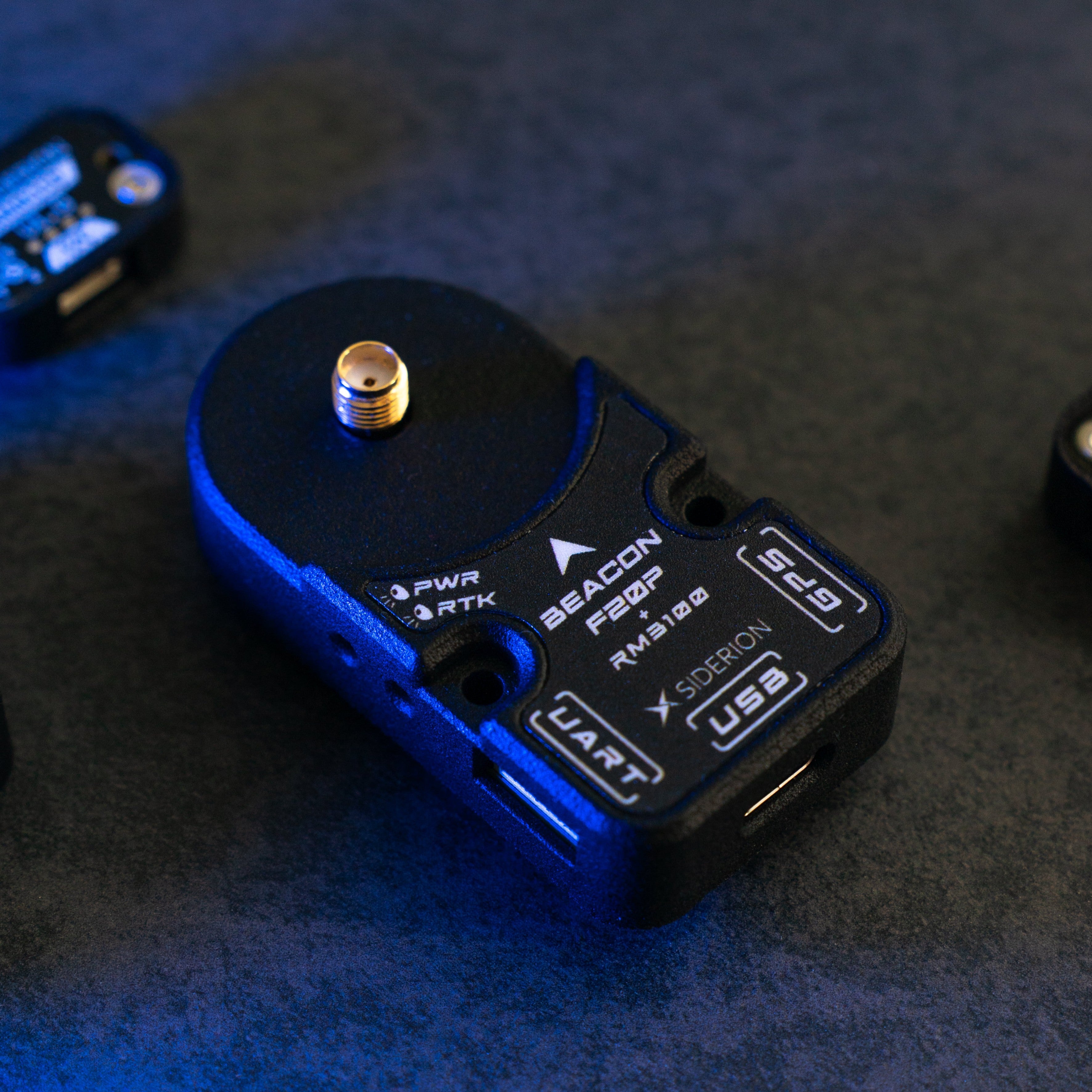 Siderion BeaconF20P RTK GNSS module based on the ZED-F20P on a dark background. Top isometric view. Blazing blue light coming from the left.