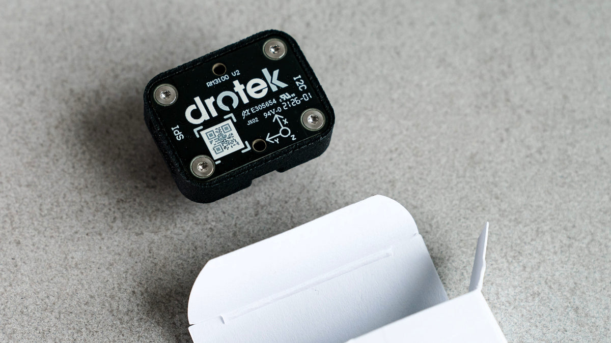 A black Siderion RM3100 electronic module with silver screws and white printed branding, shown next to an open white cardboard box on a gray textured surface.